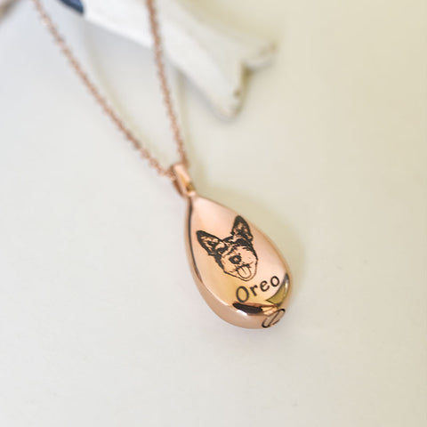 Rose gold teardrop pendant with a dog illustration and 'Oreo' engraving on a light background
