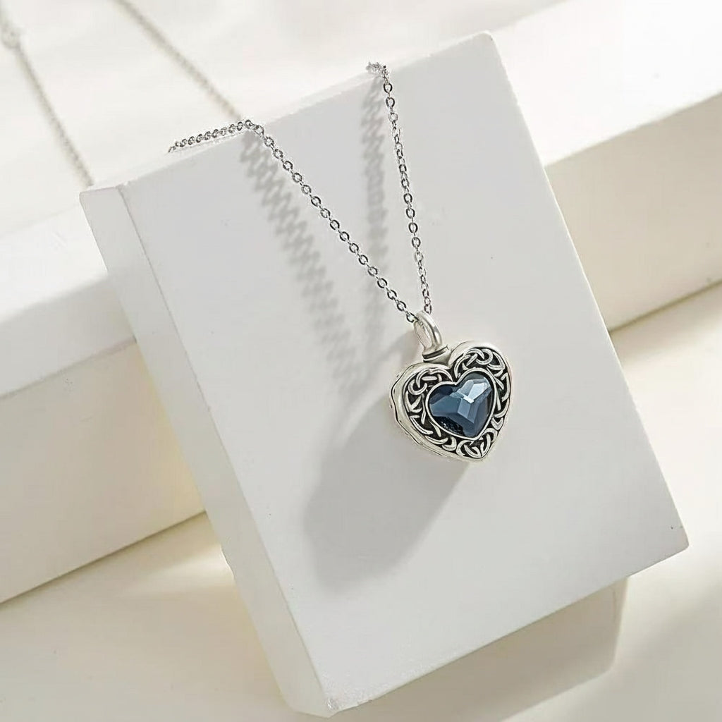 Silver necklace with a heart-shaped blue stone pendant on a white box