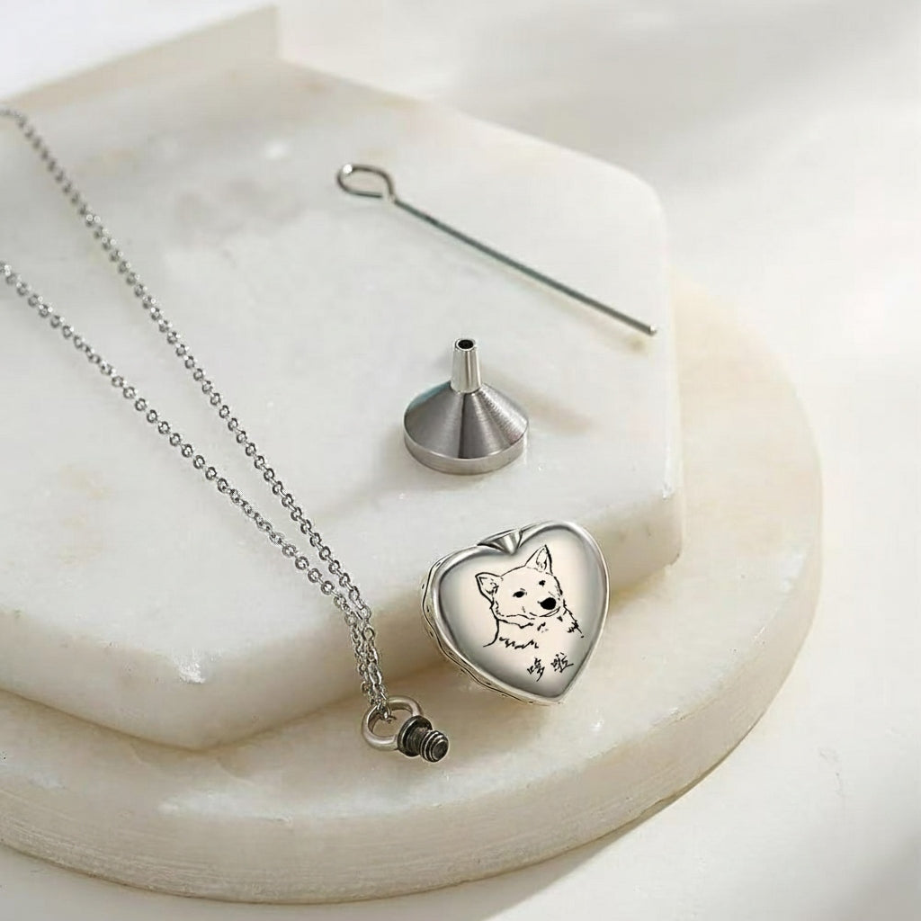 Heart-shaped silver locket with a dog design on a marble surface