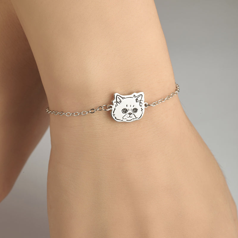 Silver cat-shaped bracelet on a wrist against a neutral background
