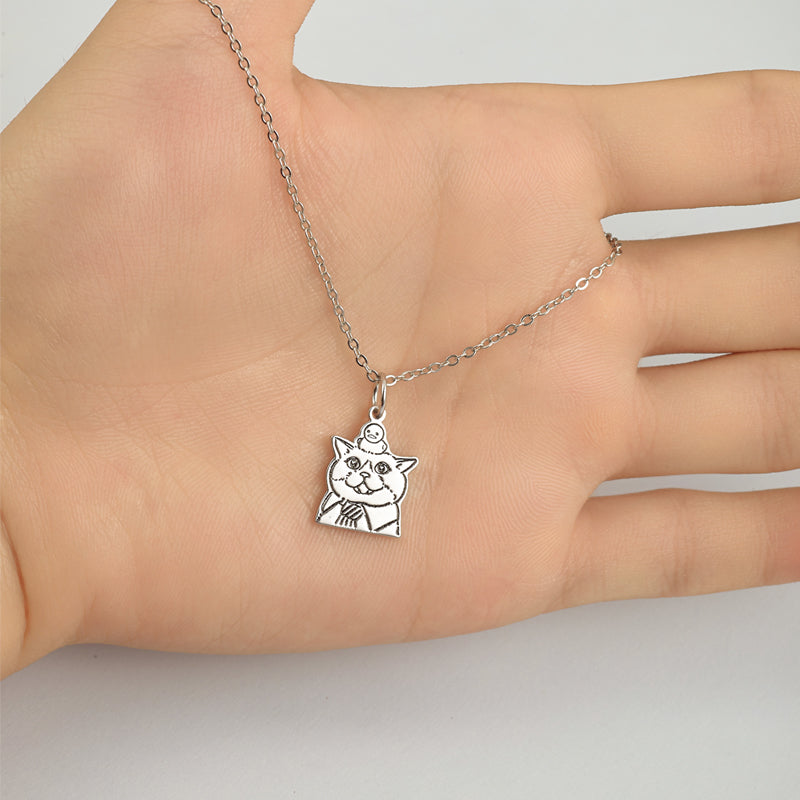 Silver cat pendant necklace on a hand against a neutral background