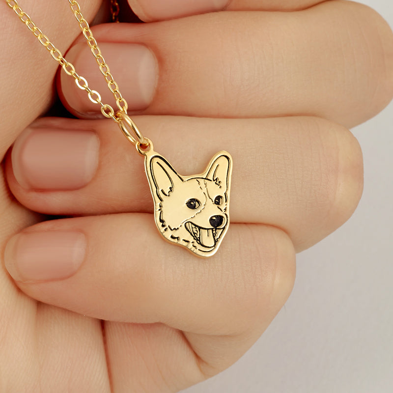 Gold dog-shaped pendant on a chain held between fingers