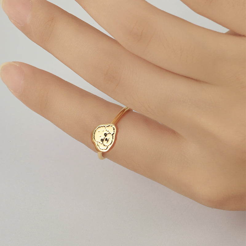 Gold ring with a heart-shaped design on a hand against a light background