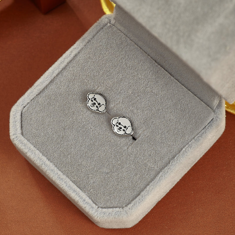 Silver earrings in a gray jewelry box on a brown surface