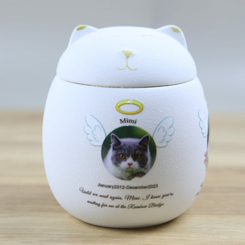 Memorial urn with a cat's face and text on a wooden surface